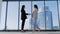 Portrait of two casual looking businesswoman meeting with background of office buildings behind the windows. Colleagues