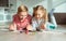 Portrait of two cheerful children laying on the floor and playing with colorful dices