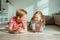 Portrait of two cheerful children laying on the floor and playing with colorful dices