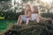 Portrait of two children girls sitting on straw bale in hay field.Light sunny day. Cheerful and calm friends concept