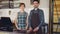 Portrait of two confident waiters in aprons standing at cashier`s desk in coffee-house and smiling. Successful business