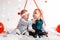 Portrait of two cute little babies pose on a white background decorated with hearts and balloons. Valentine`s day concept