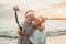 Portrait of two cute old persons having fun and enjoying together at the beach on christmas days at the beach wearing Christmas