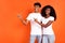 Portrait of two dark skin persons look indicate fingers empty space wear white t-shirt isolated on orange color