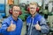 portrait two engineers in machinery workshop holding thumbs up