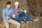 portrait of two farmers taking a pause in the hay and having their phones in hands