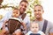 Portrait Of Two Fathers With Baby Carriers In Park