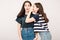 Portrait of a two girls gossip on gray background