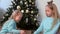 Portrait two girls sisters draw fingers on pillow sequins near Christmas tree.