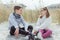 Portrait of two happy cute teen siblings sitting and joyful talking on white sand at Baltic sea beach