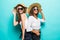 Portrait of two happy girls with different type of skin wearing straw hats and summer clothing over blue background