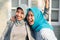 Portrait of two happy hijab women, smiling at the camera while embracing in front of their house