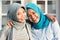 Portrait of two happy hijab women, smiling at the camera while embracing in front of their house