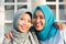 Portrait of two happy hijab women, smiling at the camera while embracing in front of their house