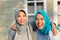 Portrait of two happy hijab women, smiling at the camera while embracing in front of their house