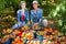 Portrait of two happy women with harvest of peaches in buckets in an orchard