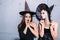 Portrait of two happy young women in black witch halloween costumes on party
