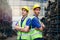 Portrait of two industrial engineer workers man wearing helmet with arms crossed, standing at manufacturing plant factory with