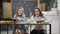 Portrait of two joyful schoolgirls talking and laughing sitting at desk in classroom in school. Positive beautiful