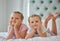 Portrait of two little girls lying on a bed at home. Smiling girls only relaxing and looking comfy, two blonde caucasian