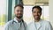 Portrait of two multiracial doctors smiling and looking at camera. Indian and caucasian smiling doctors in white coat