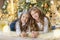 Portrait of two one young girls sisters close to white green Christmas tree. The girls in beautiful evening dresses clothes in New