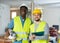 Portrait of two positive builders holding a hammer drill and working documents