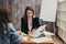 Portrait of two prett young women sitting at work desk.