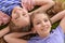 Portrait of two pretty little girls lying on green carpet and looking at camera