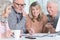 Portrait of two senior couples sitting at table and working