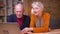 Portrait of two senior gray-haired caucasian spouses talking in videochat caressing each other tenderly in office.