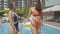 Portrait of two sensual Caucasian women posing at poolside on sunny summer day. Tanned relaxed female tourists standing