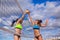 Portrait of two slim sporty girls playing beach volleyball against a bright blue sky