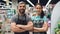 Portrait of two supermarket employees attractive people in aprons standing inside shop, smiling and looking at camera