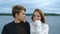 Portrait of two teenagers, a guy and a girl, against the background of a river and forest.