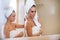 Portrait of two women applying lotion after shower, friends doing skincare procedure