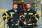 Portrait of two young firemen in uniform standing inside the fire station