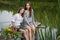 Portrait of two young girls who are sitting on a bridge on a pond