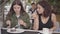 Portrait of two young women eating a cake sitting in cafe outdoors. Young girls together enjoying their meal talking