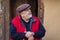 Portrait of Ukrainian bearded senior peasant sitting against old barn entry