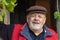 Portrait of Ukrainian bearded smiling senior peasant against old barn entry