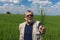 Portrait of Ukrainian senior farmer standing inside unripe crops field and holding  several spikelets as the firm belief in future