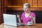 Portrait of unbelievable young girl freelancer with blonde short hair, in pink t-shirt and eyeglasses is sitting in cafe, working