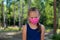 Portrait of unhappy caucasian little girl in a protective mask outdoors. Coronavirus outbreak. A disgruntled child does