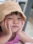 Portrait of unhappy cute little girl holding hands on chin and sitting at the desk