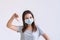 Portrait of unhappy young Asian girl with protective face mask posing thumb down over white background. Copy space