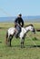 Portrait of an unidentified Mongolian man wearing traditional costume riding on horse back in a steppe in Kharkhorin, Mongolia.