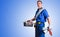 Portrait of uniformed plumber with tools and blue isolated background