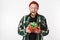 Portrait of unshaved man wearing hat and plaid shirt holding present box, while standing isolated over white background