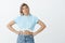 Portrait of unsure good-looking european female model in cropped top and jeans, holding hands on hips and looking at